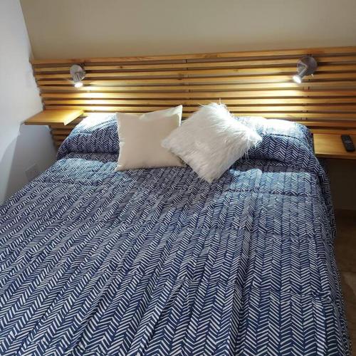 ein blau-weißes Bett mit zwei Kissen darauf in der Unterkunft Microcentro de la Docta in Cordoba