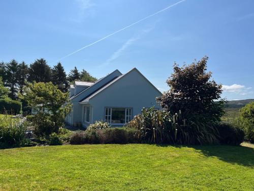 a white house with a lawn in front of it at Ballinakill Lodge in Moyard