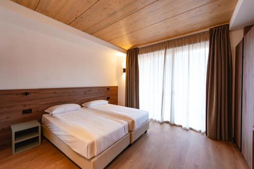 a bedroom with a large bed and a large window at mySHH in Vigo di Fassa