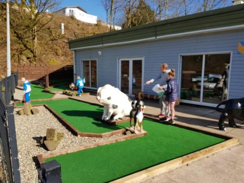 a family playing with a fake cow on a fake lawn at Beacon View Lodge in Lancashire in Longridge