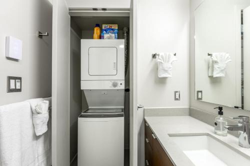 a bathroom with a washer and dryer next to a sink at Sun-Drenched Sophistication in Victoria