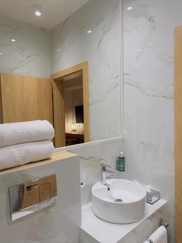 a white bathroom with a sink and a mirror at Hotel Serenity Timisoara in Timişoara