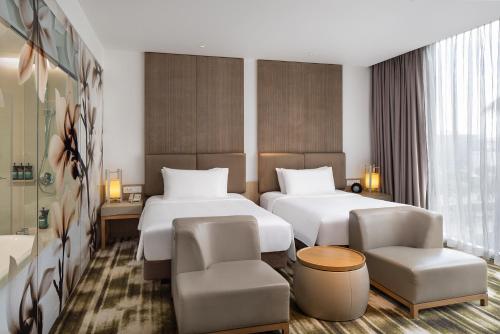 a hotel room with two beds and two chairs at Crowne Plaza Changi Airport by IHG in Singapore
