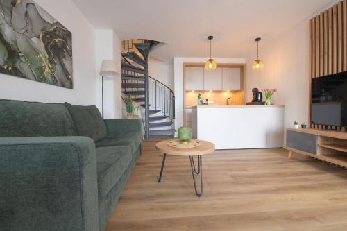 ein Wohnzimmer mit einer grünen Couch und einem Tisch in der Unterkunft Deichkrone in Carolinensiel