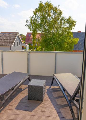 ein Balkon mit Picknicktisch und Bank in der Unterkunft Deichkrone in Carolinensiel