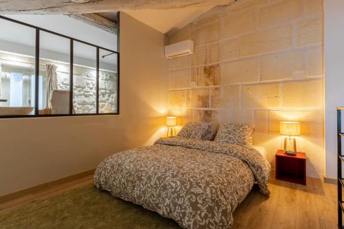 a bedroom with a bed and a brick wall at Charmante maison en Arles : La Roquette in Arles
