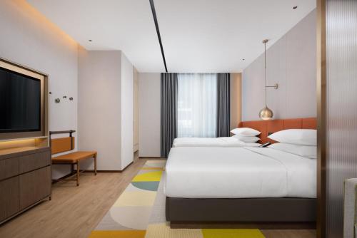 a hotel room with two beds and a flat screen tv at Home2 Suite by Hilton Jingjiang Binjiang New Town in Jingjiang