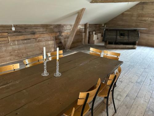 a large wooden table with chairs and candles on it at Magasinet Stora Långbro in Tystberga