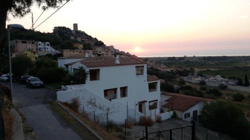 a house on a hill with the sunset in the background at Su Sole in Posada