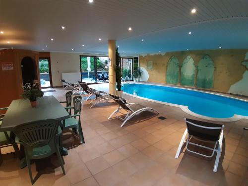 - une piscine dans une pièce avec des chaises et une table dans l'établissement Les Berges de l'Ohmbach, à Soultzmatt