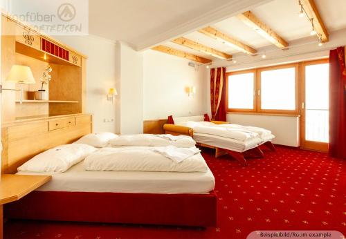 two beds in a room with red carpet at Sporthotel Christophorus in Kappl