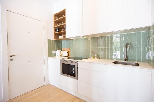 a kitchen with white cabinets and a sink at Colón 29 Apartments in Denia