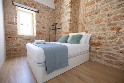 a bedroom with a bed and a brick wall at Colón 29 Apartments in Denia