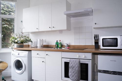 a kitchen with white cabinets and a washer and dryer at Stylish Swindon Town Centre Apartment, FREE parking, sleeps up to 3 in Swindon
