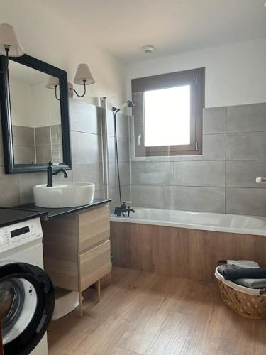 une salle de bain avec une baignoire, un lavabo et un miroir dans l'établissement Maison Les Pins, à Lagorce