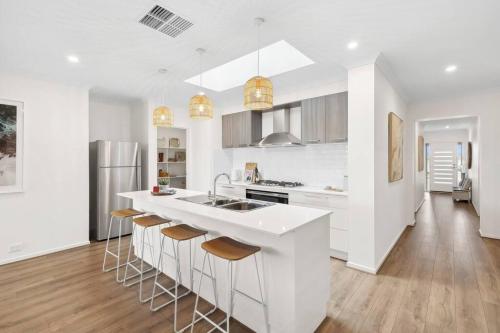 a white kitchen with a sink and bar stools at Modern Seaside Escape on the Coast in Ocean Grove