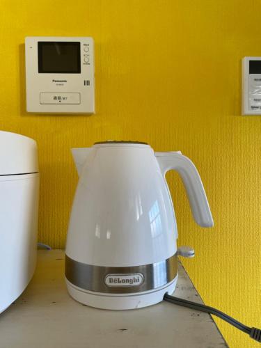 a tea kettle sitting on a counter next to a microwave at 一棟貸し宿ゲストハウスサンク in Masuda