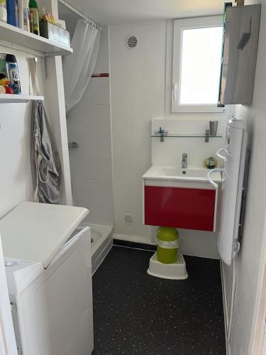 - une petite salle de bains blanche avec lavabo rouge et fenêtre dans l'établissement La Villa K NARD au centre de Saint Trojan, à Saint-Trojan-les-Bains