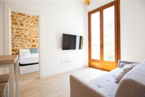 a living room with a couch and a tv on a wall at Colón 29 Apartments in Denia