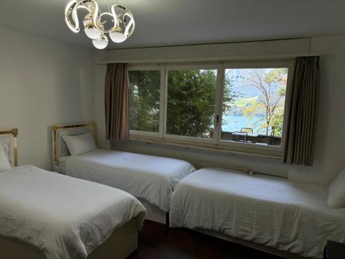 Dos camas en una habitación con ventana y lámpara de araña. en Luzern See, en Lucerna