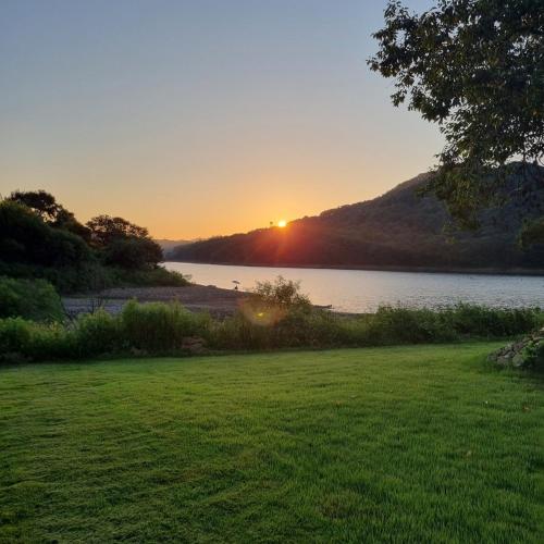 a sunset over a body of water with a grass field at Cheongna Stay in Sŏch'on