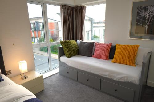 a bedroom with a couch with colorful pillows on it at Luxury Rooms - Pick a Room - Free Parking & Kitchen Access, Near Etihad Stadium, The Coop Live & Piccadilly Station, Manchester in Manchester
