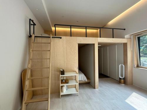 a loft bed with a ladder in a room at Gangchon 1225 Pension in Chuncheon