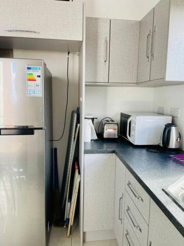 a kitchen with a refrigerator and a microwave at Cozy 2-Bedroom Apt, 10mins Walk to Beach - GBHC3 in The Vale