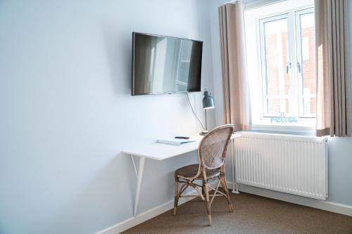 a desk with a chair and a television on a wall at Hotel Marie in Skagen