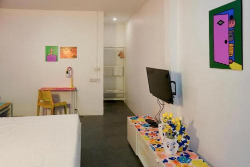 a room with a tv on a wall with a table at BW Thai Art Style Hotel in Bangkok