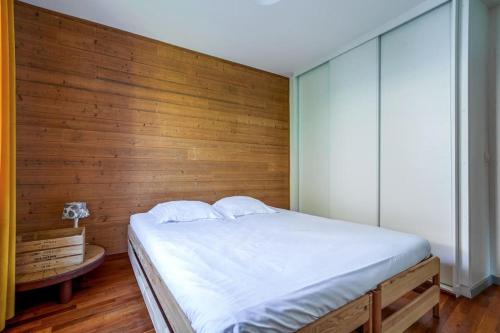 a bedroom with a white bed and a wooden wall at Maison de ville proche Chenonceau Amboise 8 p in Bléré