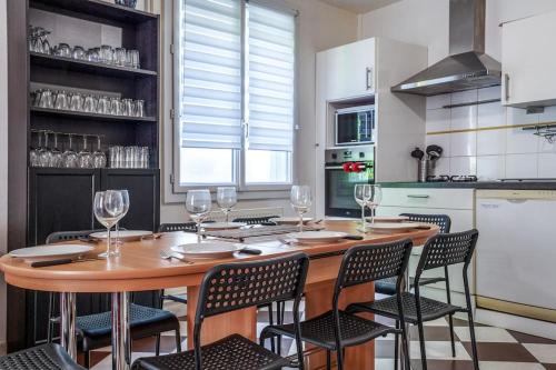 a kitchen with a wooden table and chairs with wine glasses at Maison de ville proche Chenonceau Amboise 8 p in Bléré