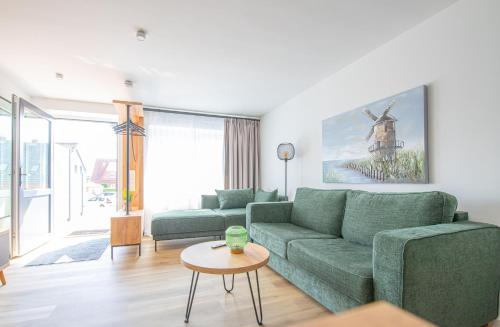ein Wohnzimmer mit einer grünen Couch und einem Tisch in der Unterkunft Sonnenblick in Carolinensiel