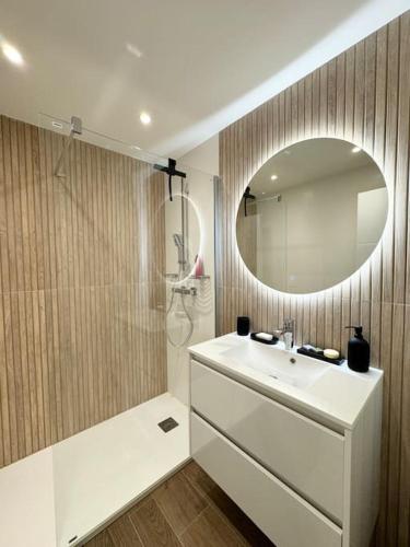 une salle de bain avec un lavabo blanc et un miroir dans l'établissement Le cosy, appartement de charme rénové en bord de mer à Bénodet, à Bénodet
