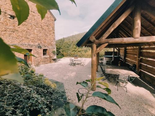 an outdoor patio with chairs and a building at Le Trou 14, Ancienne ferme dans la nature avec bain nordique in Ferrières