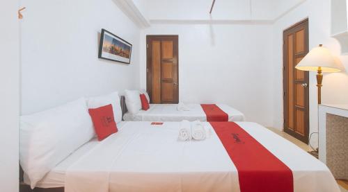two beds in a white room with red and white at RedDoorz near LRT 2 Antipolo Station in Antipolo
