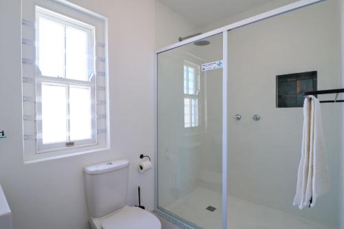 a white bathroom with a toilet and a shower at Dreamcatcher Rosemary in Paternoster