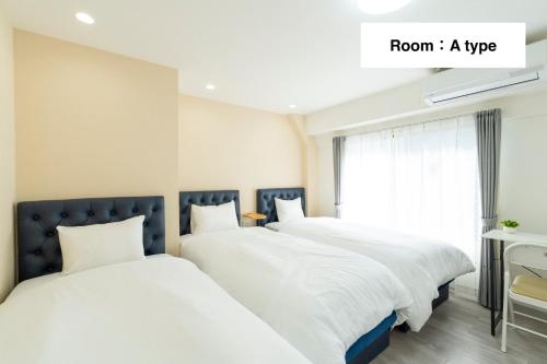 two beds in a room with a window at Kyoto Waka Hotel in Kyoto