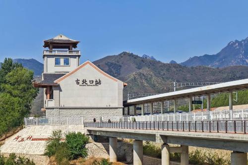 a building with a clock tower next to a bridge at Gubeikou Great Wall Yunyeshu Boutique Guesthome in Miyun