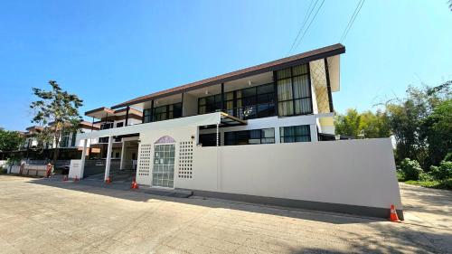 a large white building with a fence in front of it at PhuriPoolvilla ภูริพูลวิลล่า in Hang Dong