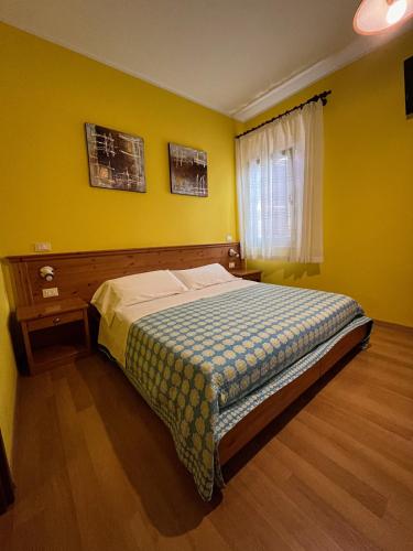 a bedroom with a bed with yellow walls and a window at Corte Bussari in Arquà Polesine