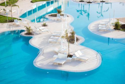 an island in the middle of a swimming pool with white lounge chairs at GF Victoria in Adeje
