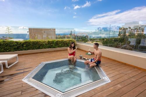 a man and a woman sitting in a hot tub on a balcony at GF Victoria in Adeje