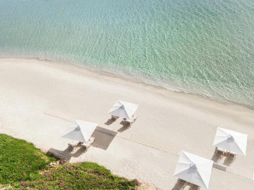 an overhead view of a beach with white umbrellas at Ikos Olivia in Gerakini
