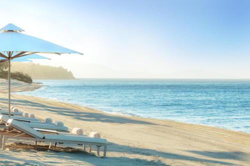 a group of chairs and an umbrella on a beach at Ikos Olivia in Gerakini
