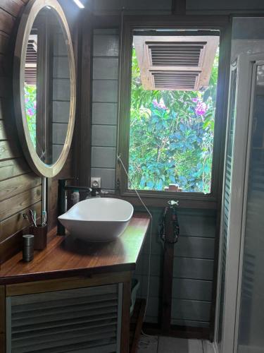 a bathroom with a white sink and a window at Villa Nature caraïbe lodge, vue mer, piscine privée in Deshaies