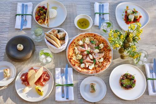 a table with plates of food and a pizza at Ikos Olivia in Gerakini