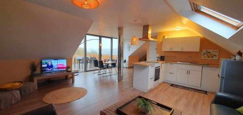 a living room with a kitchen and a living room with a tv at La Maison du Sabotier in Custinne