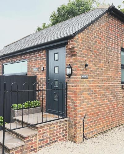 a brick building with a black door and a gate at Rife Lodges in Arundel
