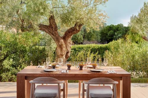 a wooden table with wine glasses on it in front of a tree at Ikos Olivia in Gerakini